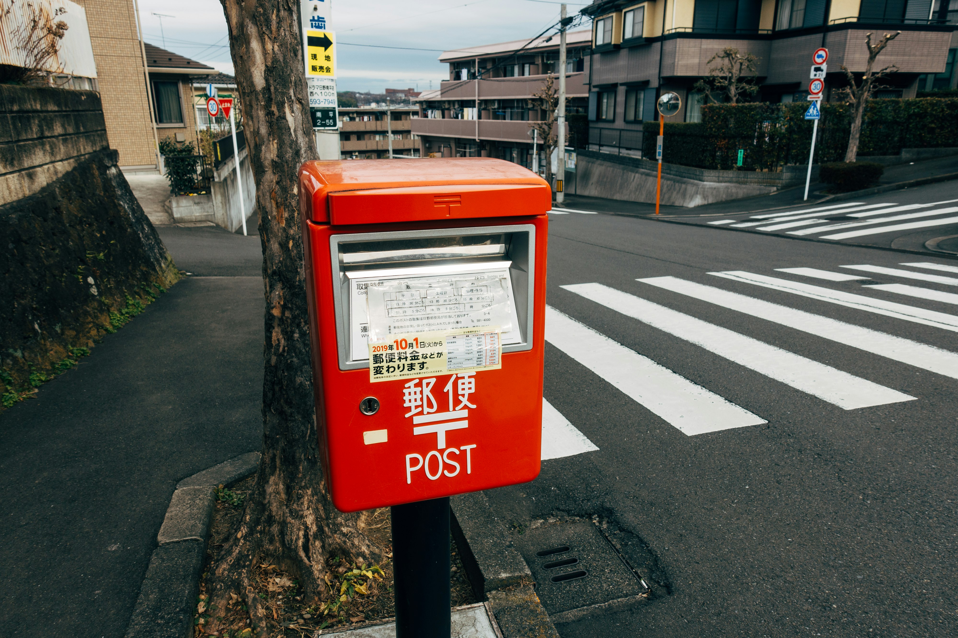 red and white mail box on gray asphalt road during daytime